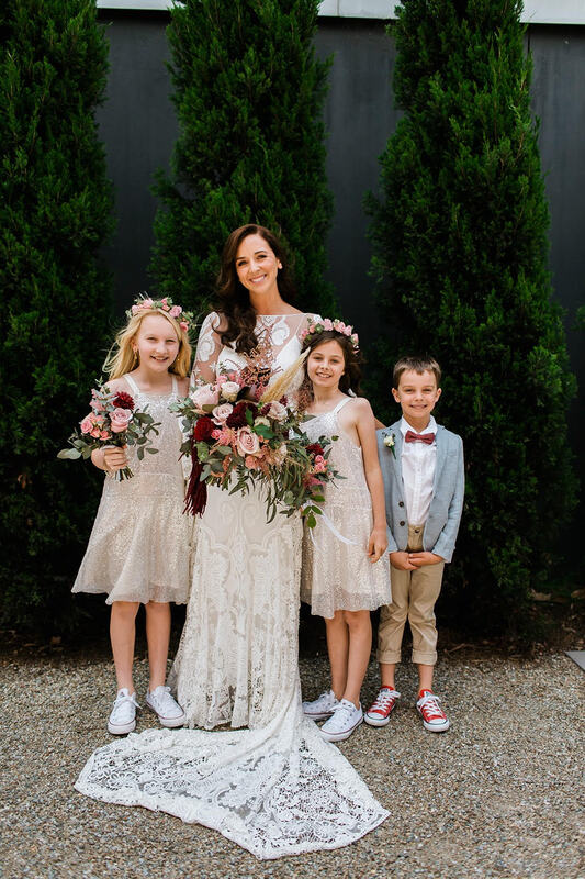 Bride with flower girls and page boy. Flower girls are wearing crowns of eucalyptus and rose buds. 
