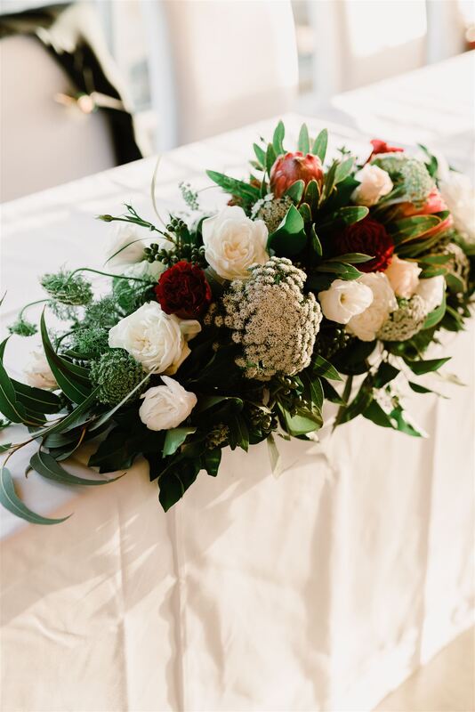 Wedding table centrepiece, long and low arrangement of roses, proteas and queen anne lace. 