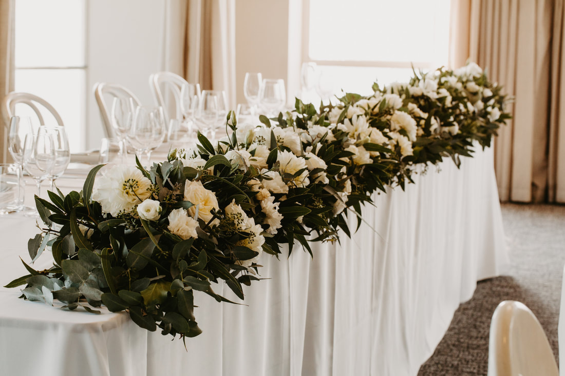 Rustic bridal table floral runner with white roses and dahlias and green eucalyptus and gum foliage. 