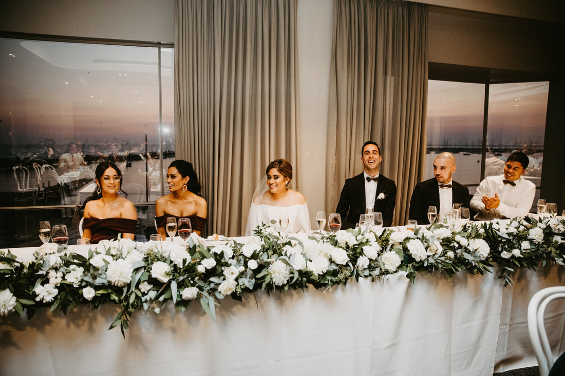 Bridal table at Harbour Room St Kilda with a full floral runner of white and green flowers including dahlias and roses. 