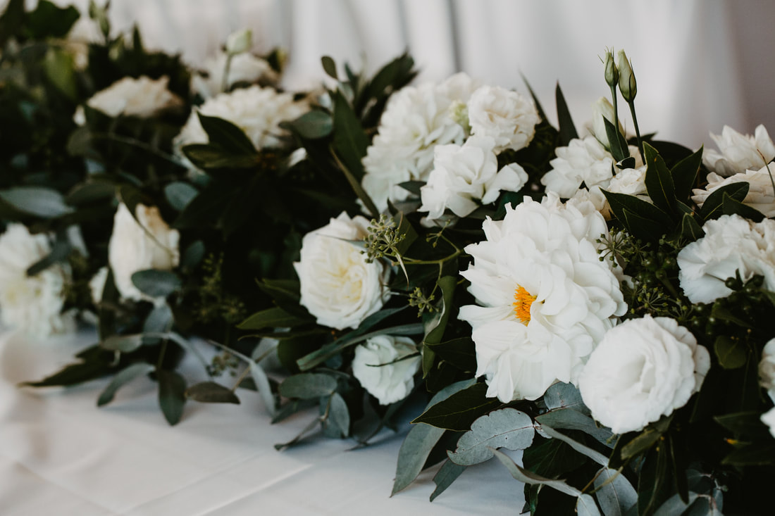 Bridal table floral runner of white and green roses dahlias and eucalyptus