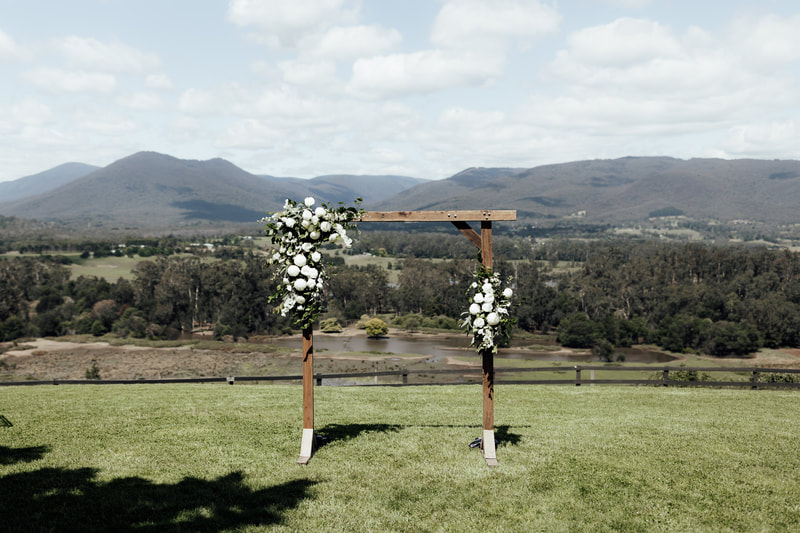 Wedding flower arbour at The Riverstone Estate, Coldstream. The arbour is decorated in the left corner with white and green flowers. 