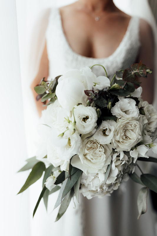 Wedding flower bouquet of white roses, hydrangea, lisianthus and eucalyptus leaves.