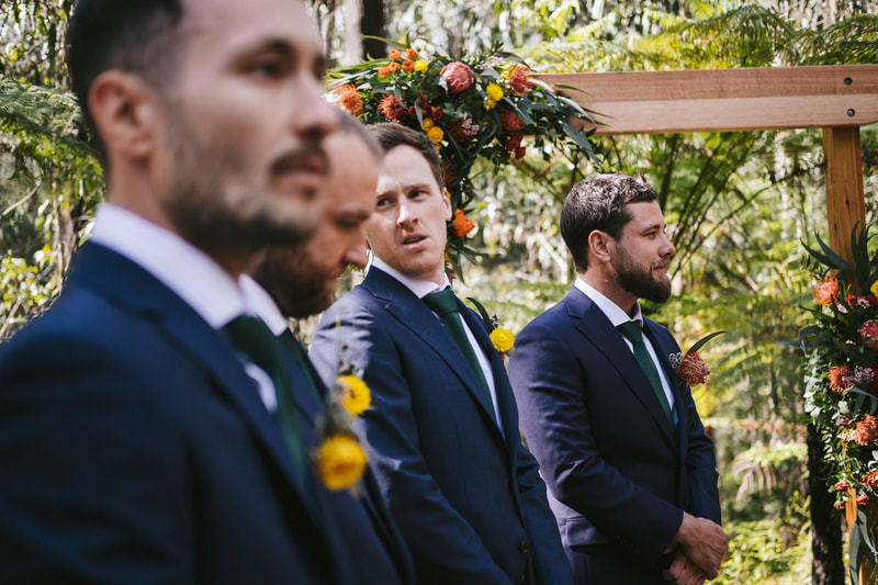 Groom and groomsmen wait for bride under rustic arbour at Forest Weddings in Kinglake