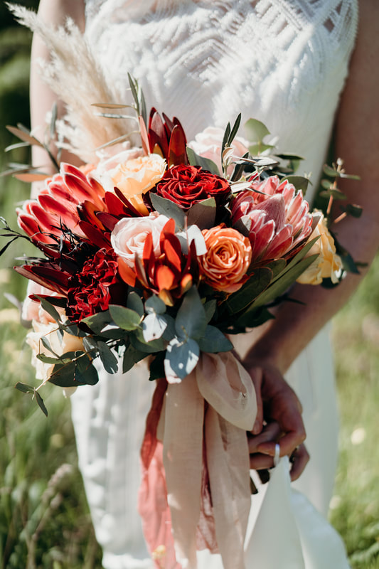 Bridal bouquet of roses, proteas and eucalyptus in burnt orange, burgundy and silver
