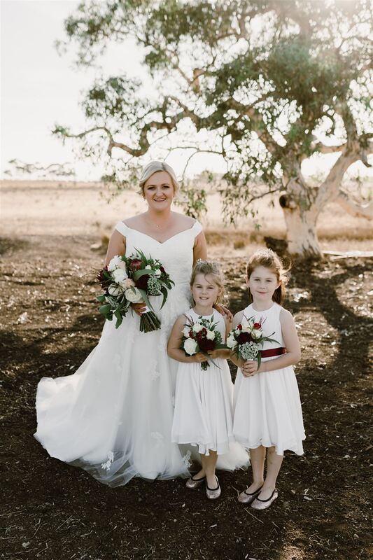 Bride and flower girls with bouquets of roses, dahlias, eucalyptus and queen anne lace in white, green and burgundy
