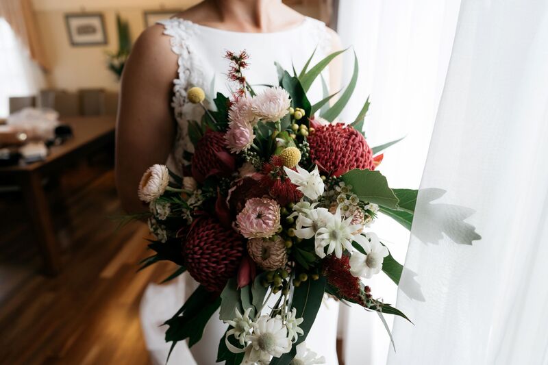 Native flower bouquet of red waratah, white flannel flower, pink strawflower, eucalyptus and billy buttons. 