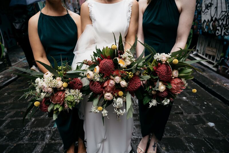 Bridesmaids in teal dresses holding native flower bouquets