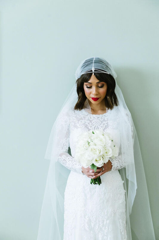 Elegant bride holding white rose bouquet with modern veil. 