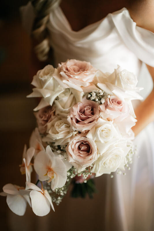 Bridal bouquet of reflexed white and blush roses with babies breath and orchid. 